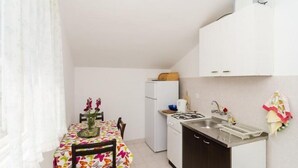A compact kitchen with a dining table, a refrigerator, a stove, and a sink.