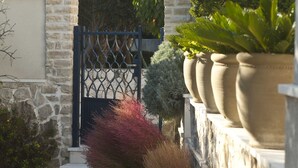 A stone building with a metal gate, potted plants, and a pathway. - Holiday home  Ingrid - Four Bedroom Holiday Home with Pool (Okrug Gornji)