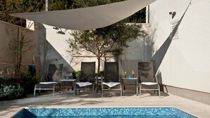A poolside area with a tiled pool, lounge chairs, and a pergola providing shade. - Holiday home  Ingrid - Four Bedroom Holiday Home with Pool (Okrug Gornji)
