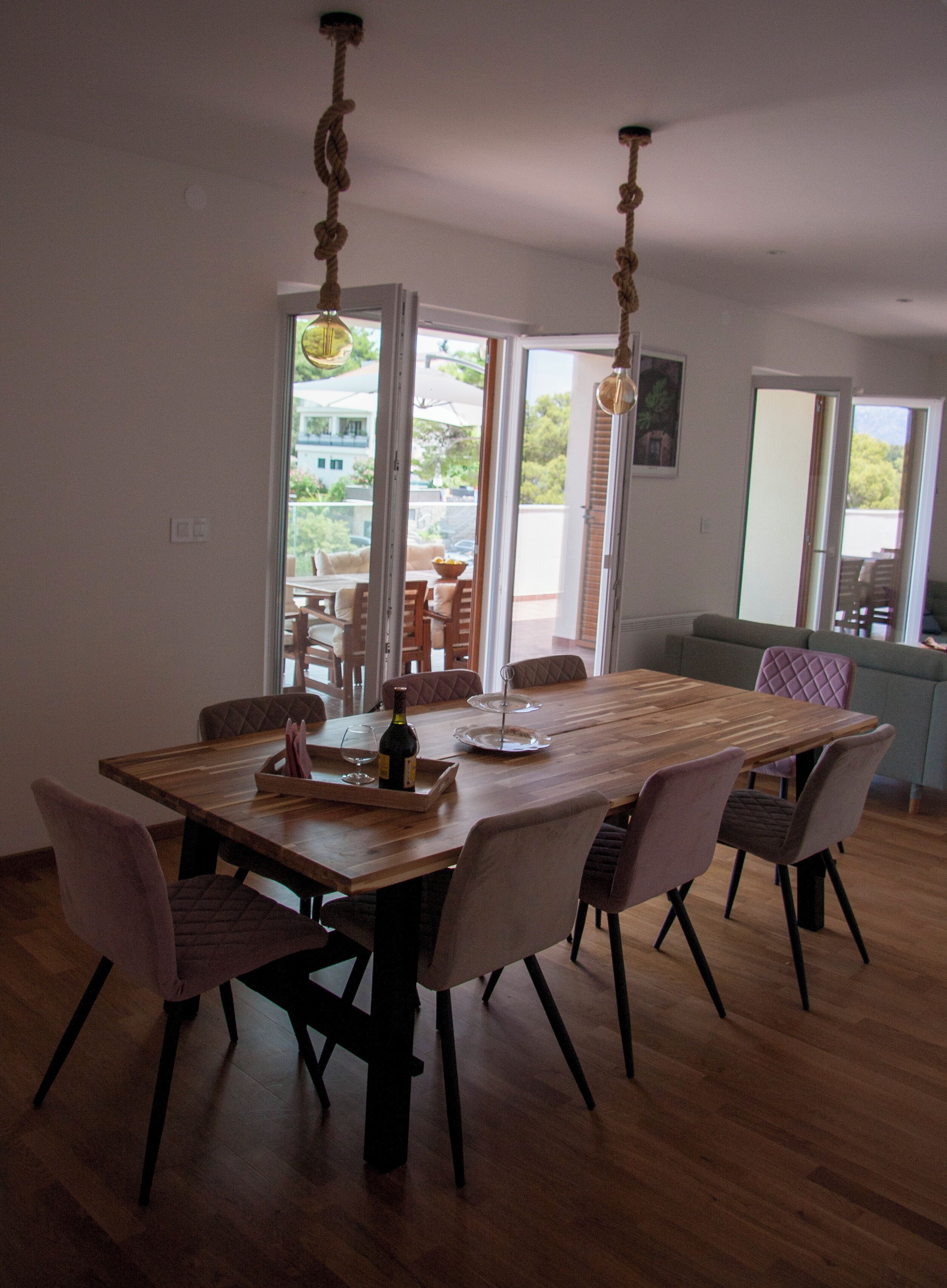 A dining area with a wooden table, six chairs, and a bottle of wine.
