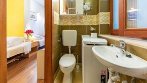 A compact bathroom with a toilet, sink, and a mirror above the sink.