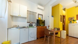 A compact kitchen with a washing machine, microwave, and a dining area with a table and chairs.