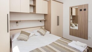 A bedroom with a bed, a mirror, and built-in wardrobes.