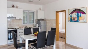 A modern kitchen with white cabinets, a dining table with chairs, and a refrigerator.