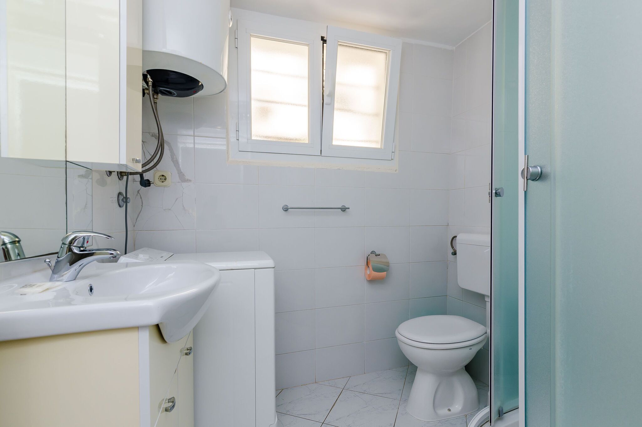 Een badkamer met een witte wastafel, toilet en douche.