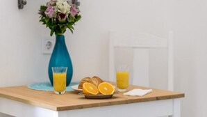 Un desayuno con croissants, gajos de naranja y zumo de naranja sobre una mesa de madera.