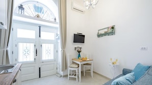 Una habitación luminosa con una mesa de comedor, sillas, un televisor y un sofá.
