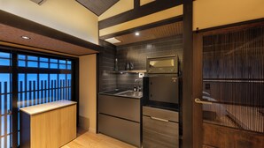 A compact kitchen with a built-in microwave, sink, and refrigerator, featuring dark cabinetry and a wooden countertop. - Kanade GionRokuhara (Kyoto)