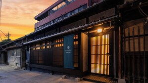 A traditional Japanese building with a modern upper floor, a sign reading "KANADE," and a well-lit entrance. - Kanade GionRokuhara (Kyoto)