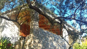 Un edificio de piedra con una ventana y un árbol frente a él.
