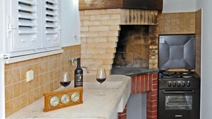 Una cocina con un horno de ladrillo, una estufa y un reloj sobre la encimera.