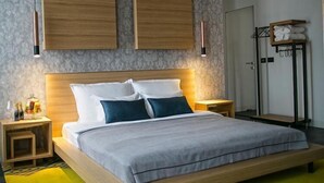 Een moderne hotelkamer met een groot bed, houten hoofdeinde, nachtkastjes en een inbouwkast.
