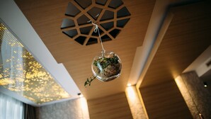 Een modern interieur met een geometrisch plafondontwerp, een hangende bol met groen en gestructureerde wanden.