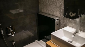Ett modernt badrum med en vit tvättställ, ett svart skåp och en duschavdelning med glasväggar.