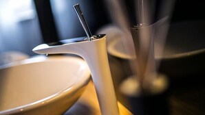 Uma mesa moderna com um prato branco, uma xícara branca e um copo transparente com canudo.