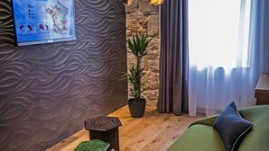 A room with a green sofa, a small wooden table, a potted plant, and a wall-mounted map. - Rooms Lejletul (ST) - Family Double Room with Square View (Miradž) (Split)