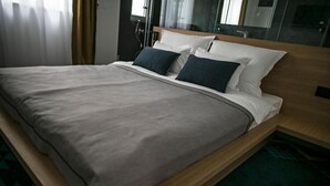 A modern hotel room with a bed, a wooden headboard, and a glass partition. - Rooms Lejletul (ST) - Family Double Room with Square View (Miradž) (Split)