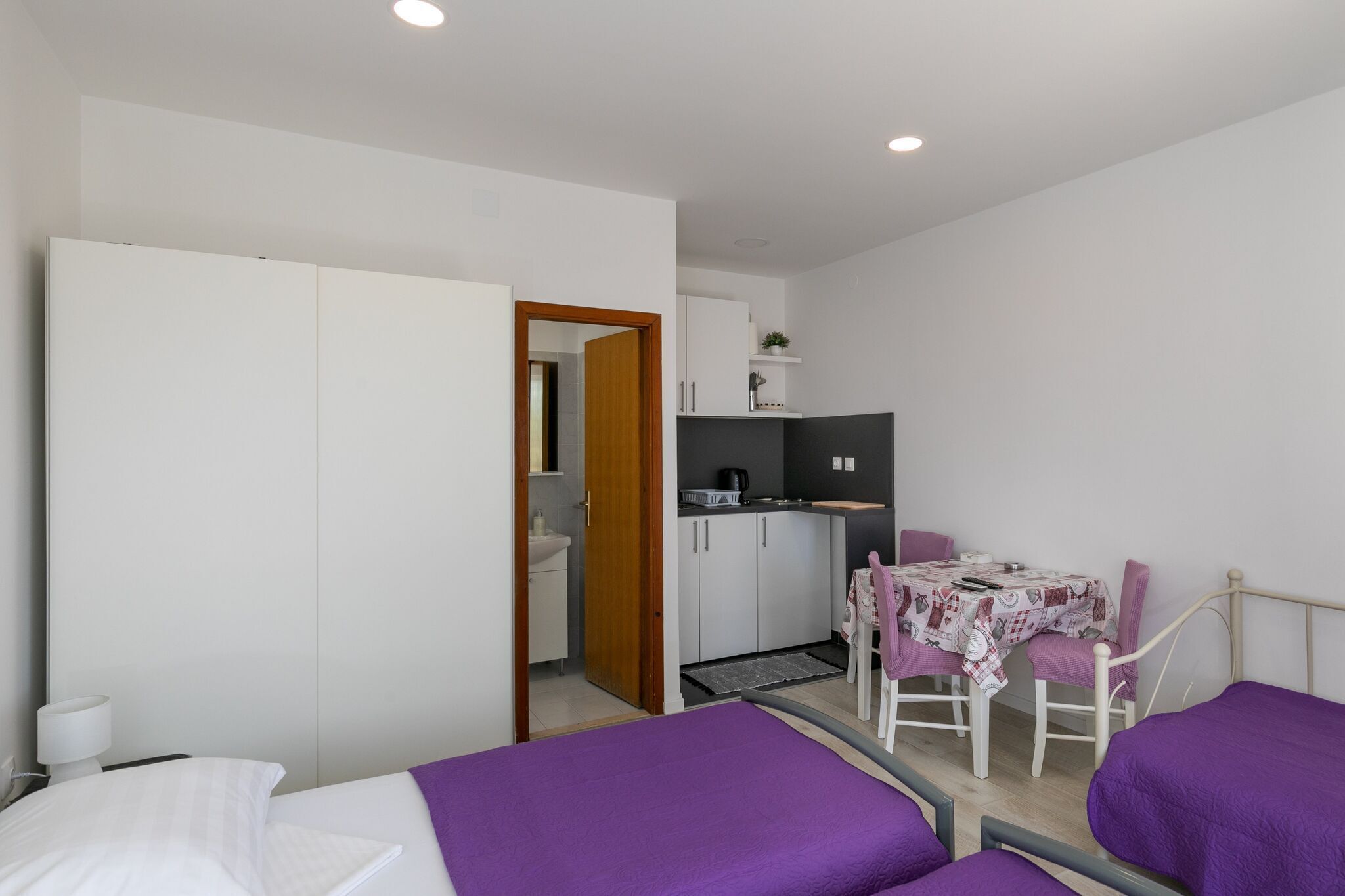 A compact room with a bed, a small kitchenette, and a dining area.