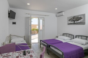 Une chambre avec deux lits, une télévision et un tableau.