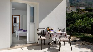 Un balcón con una mesa dispuesta para el desayuno, una silla y vistas a la vegetación y colinas circundantes.