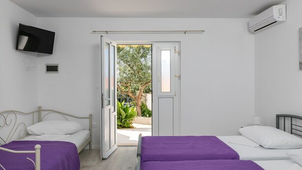 Un dormitorio con dos camas, un televisor y una puerta abierta que da a un balcón.