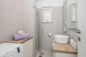 A modern bathroom with a glass-enclosed shower, a wooden vanity with a sink, and a built-in toilet.