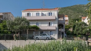 Ein zweistöckiges Gebäude mit rotem Ziegeldach, einem Balkon und einem geparkten Auto davor.