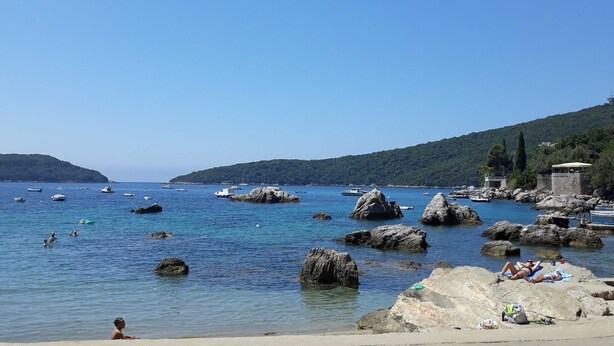 Un paysage côtier avec des affleurements rocheux, une eau d’un bleu limpide et des bateaux.