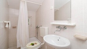 Ein Badezimmer mit Toilette, Dusche, Waschbecken und Spiegel.