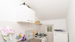 Eine kleine Küchenzeile mit Spüle, Herd und einem Fenster mit Jalousien.