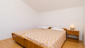 Ein Einzelbett mit gemustertem Bettbezug, ein Nachttisch mit Lampe und ein Holznachttisch.