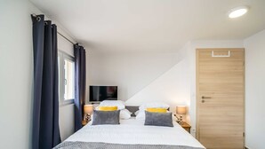 Ein Schlafzimmer mit einem großen Bett, zwei Nachttischlampen, einem Fernseher und einer Holztür.