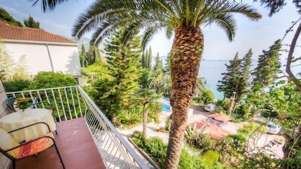 Un balcone con una sedia e un tavolo, affacciato su una piscina e vista mare.