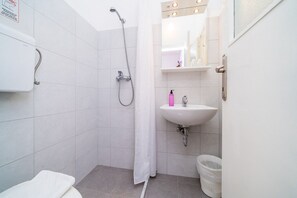 A small, modern bathroom with a shower, toilet, and sink.