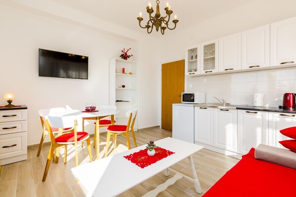 Una cocina moderna con armarios blancos, un microondas y un hervidor rojo.