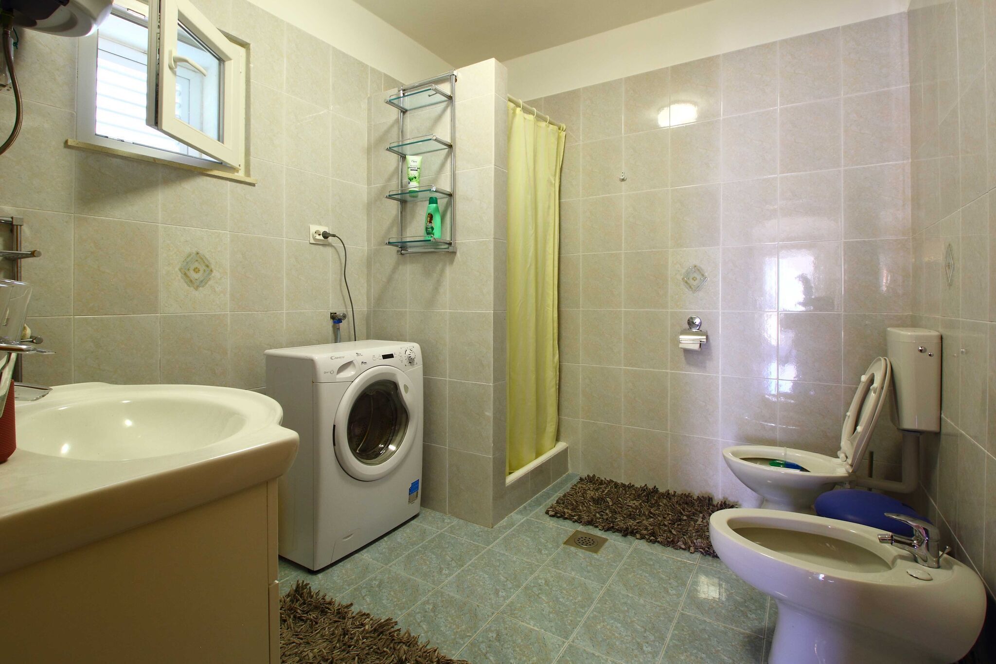 Ein Badezimmer mit Waschbecken, Waschmaschine, Toilette und Duschvorhang.
