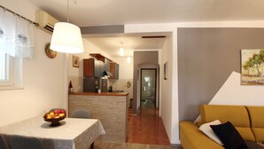A modern kitchen with a central island, a dining table with chairs, and a living area with a sofa. - Apartment Marita - One Bedroom Apartment with Balcony (Cilipi)