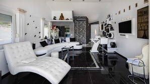 A modern living room with a white sofa, a curved white armchair, and a black tiled floor. - Apartment OM - One Bedroom Apartment with Balcony and Sea view (Povlja)