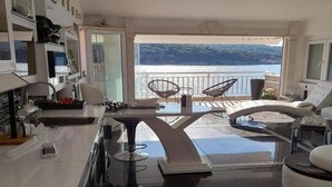 A modern kitchen with a view of the sea, a dining area with two chairs, and a balcony with a view. - Apartment OM - One Bedroom Apartment with Balcony and Sea view (Povlja)