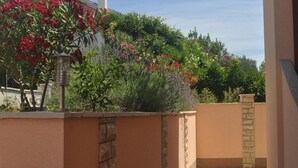Ein Garten mit unterschiedlichen Pflanzen und Blumen, eine Steinmauer und ein Laternenpfosten.