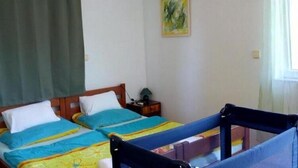 Een kamer met twee bedden, een nachtkastje, een schilderij aan de muur en een raam met gordijnen.