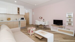 Una sala moderna con sofá, una mesa de centro, televisor y un comedor con mesa y sillas.