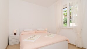 Un dormitorio con cama, mesitas de noche y ventana con cortinas.
