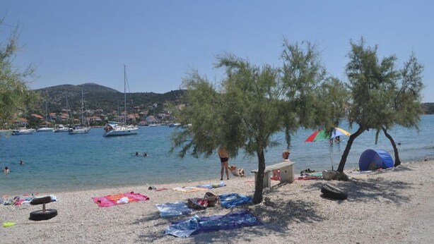 Ein Strand mit Booten, einem Zelt und einer Person am Wasser.