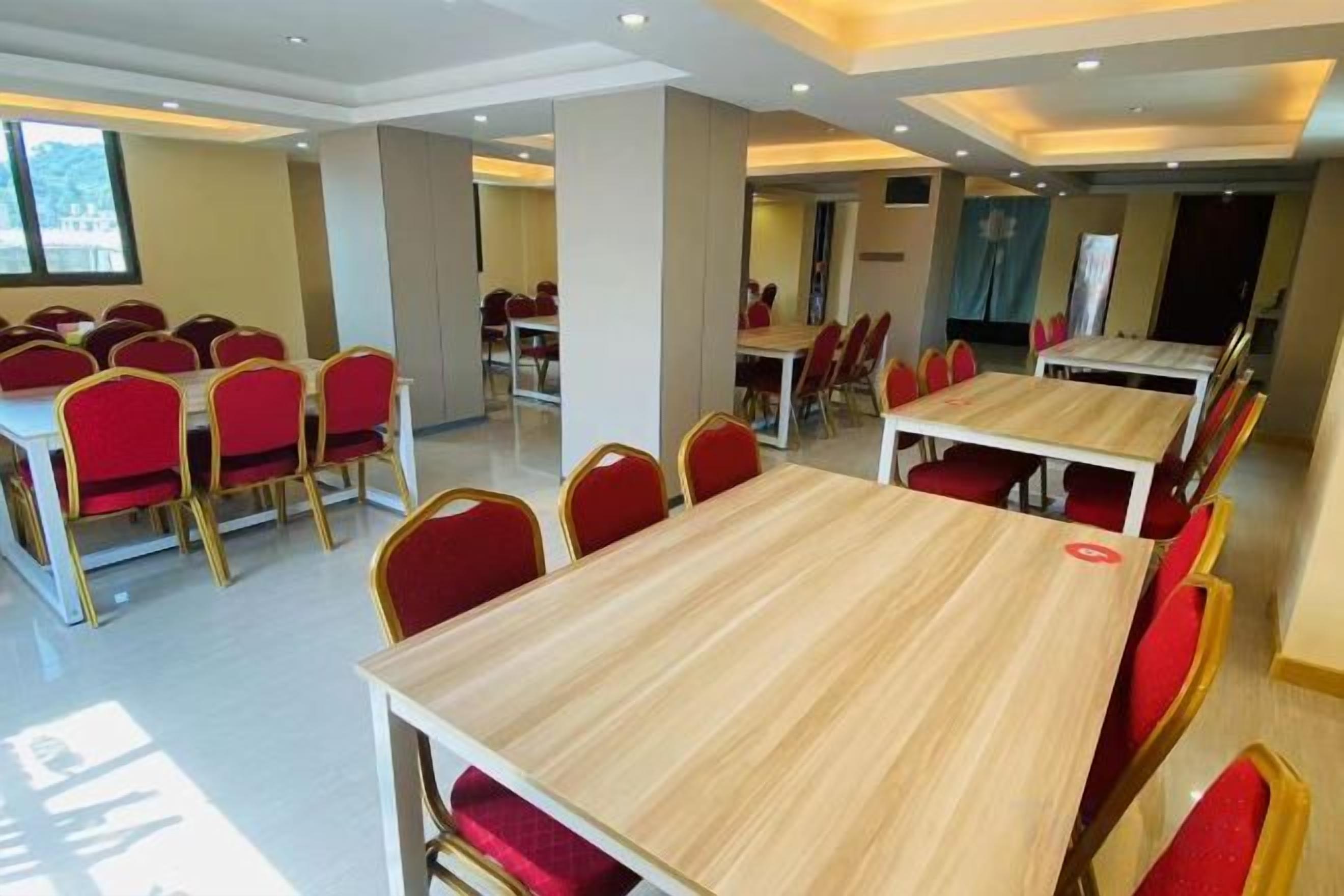 A conference room with multiple tables and chairs, arranged in rows.