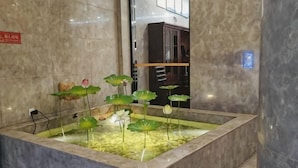 Un hall au sol en marbre agrémenté d’un élément décoratif aquatique où sont plantés des lotus.