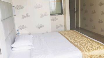 A hotel room with a bed, a window, and a door leading to a bathroom.