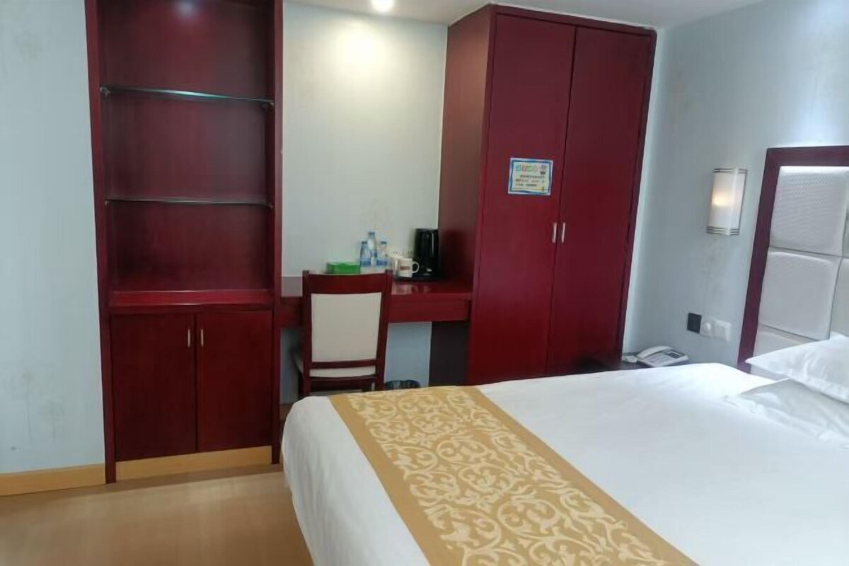 A hotel room with a bed, a desk, and a wardrobe.