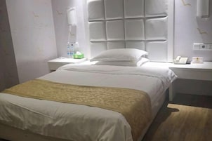 Habitación de hotel con cama, mesita de noche y ventana con vistas.