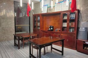 A room with a wooden table, chairs, a cabinet with books, and a wall-mounted coffee machine. - Liansheng Hotel (Fuding Taiyushan Branch) (Fuding)